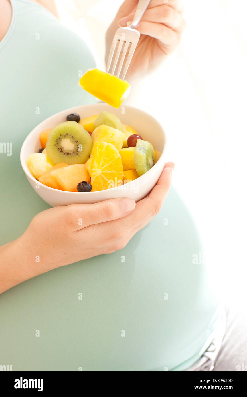 Pregnant woman eating a fruit salad. Stock Photo