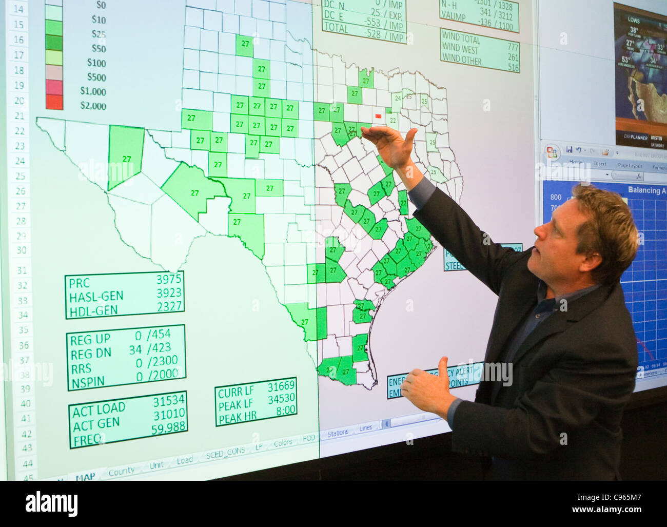 White male points to area of Texas map on computer screen at the electric reliability council of Texas (ERCOT) command center. Stock Photo