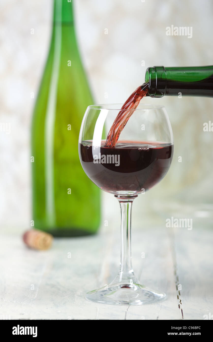 Red wine is poured from a bottle into a glass. Stock Photo