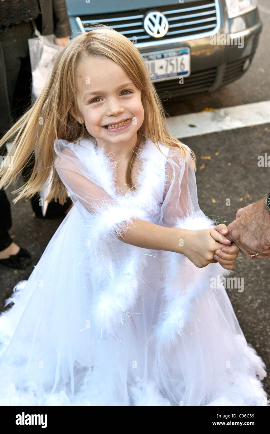 pretty little girl with flyaway golden hair dressed as a Halloween fairy princess holds her dad's finger in Hells Kitchen NYC Stock Photo