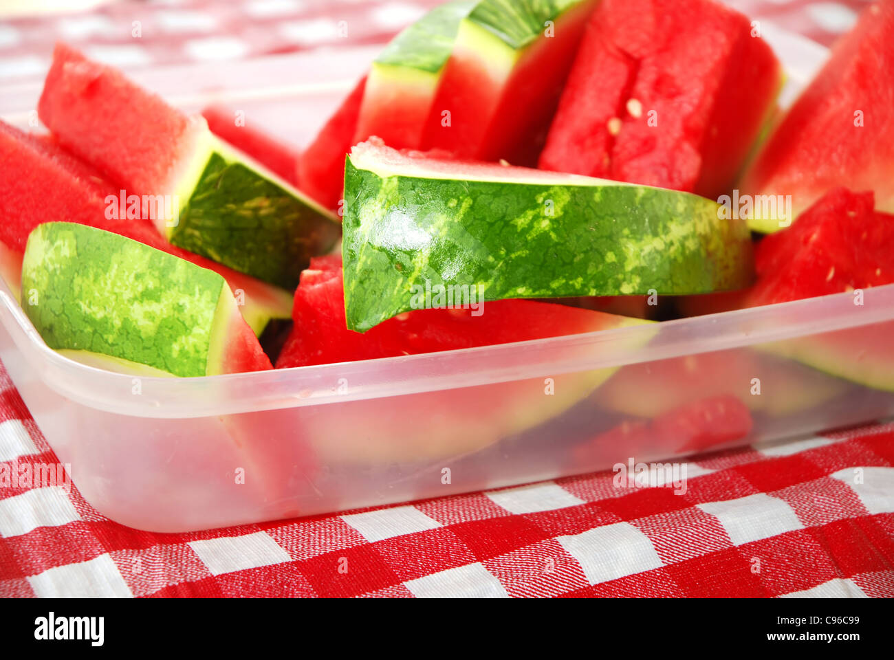 Plastic tub filled with watermelon wedges on picnic table Stock Photo