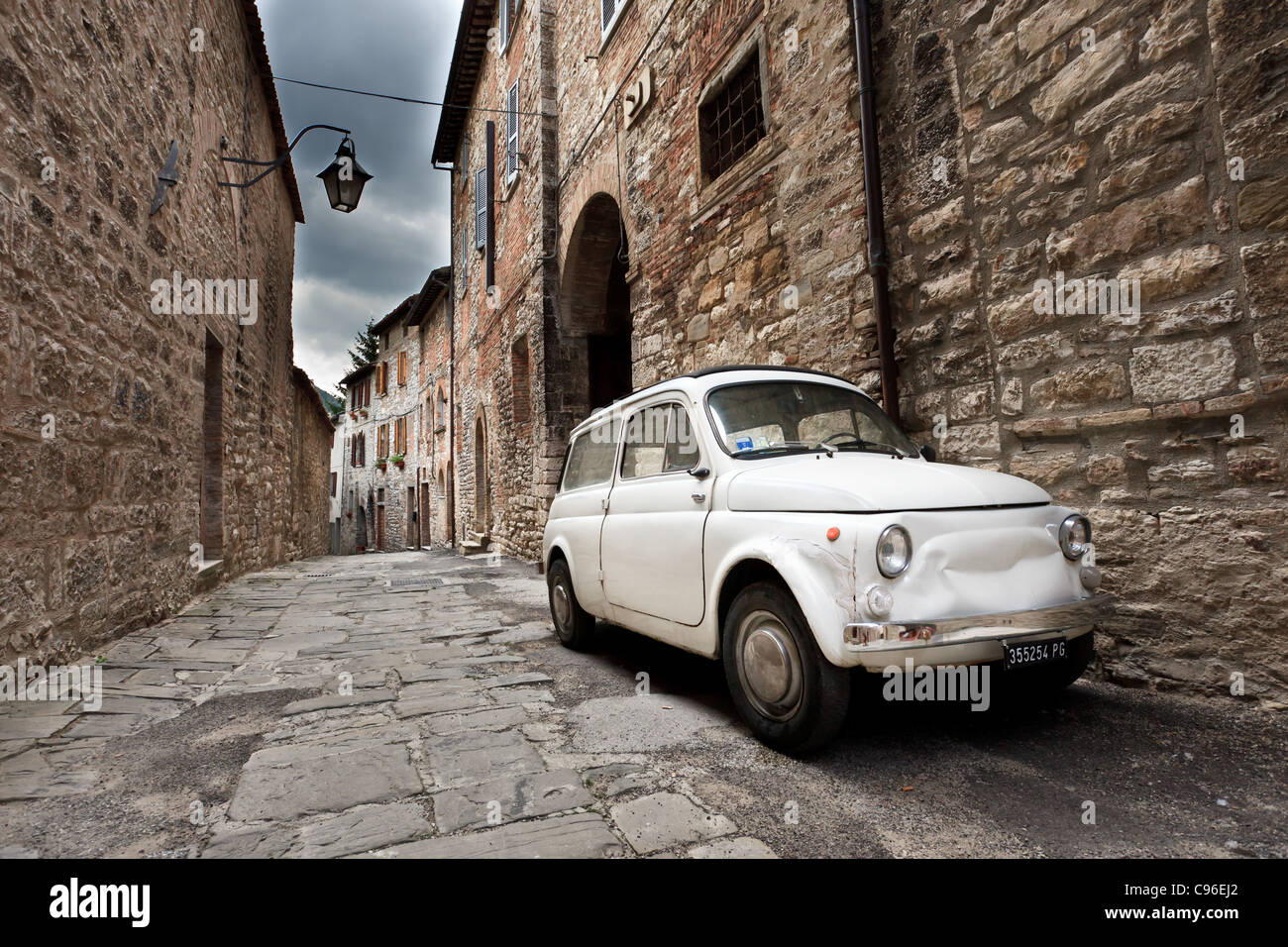 Fiat 500 car parked outside traditional Italian buildings in Gubbio