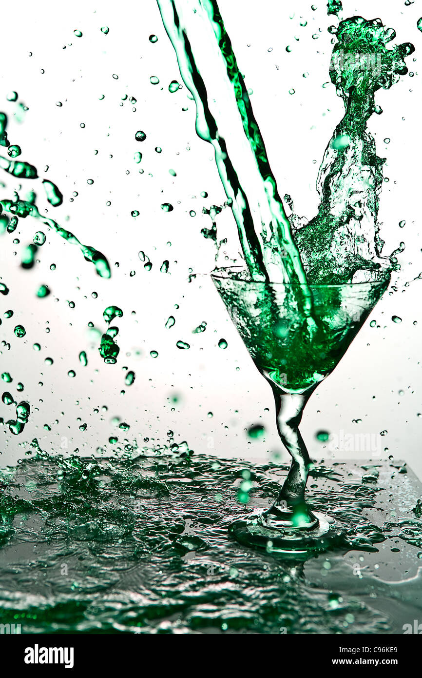 Green Liquid Pouring and splattering in martini glass Stock Photo