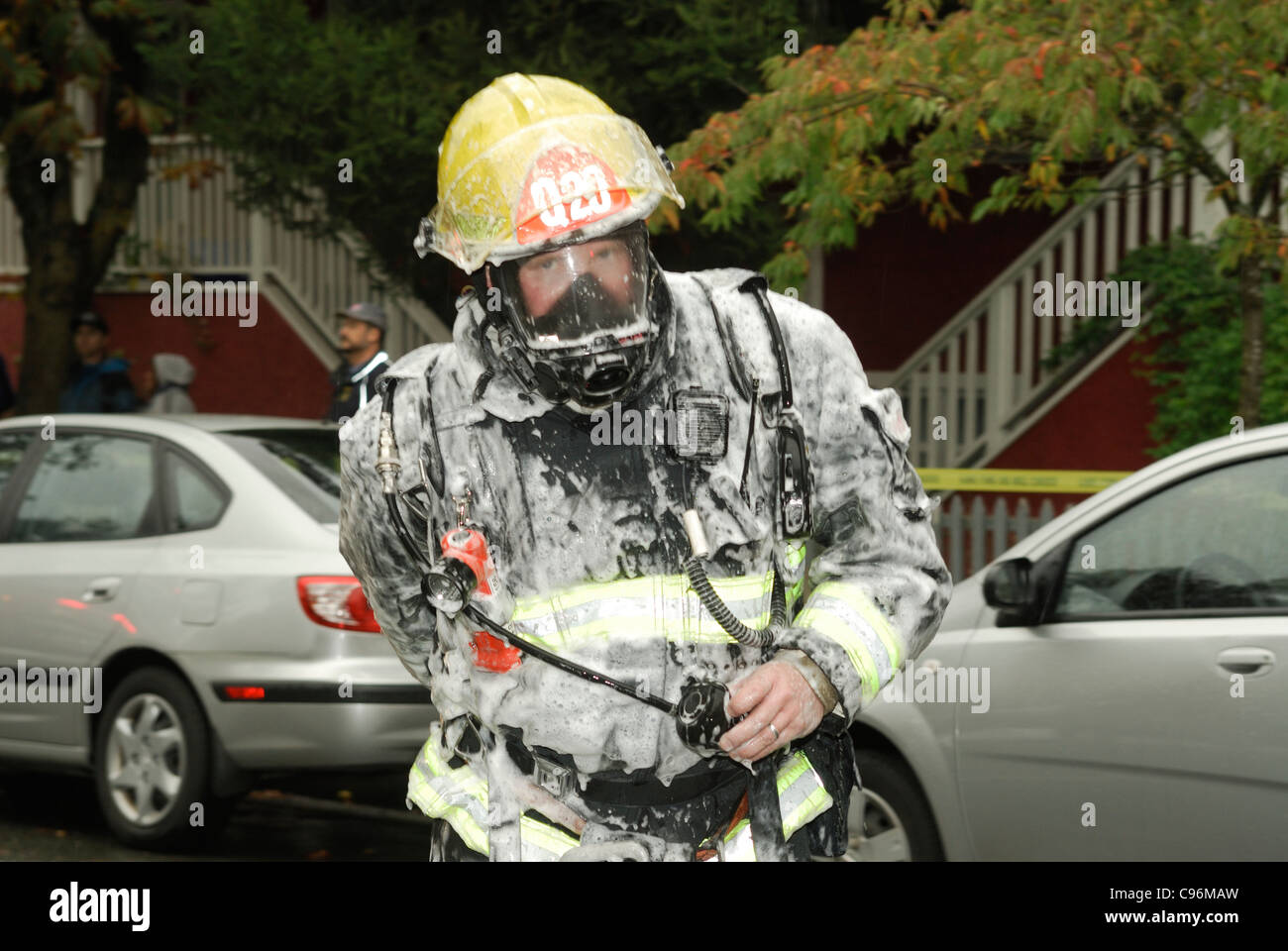 Vancouver firefighter with self contained breathing apparatus and personal protective equipment on covered in foam. Stock Photo
