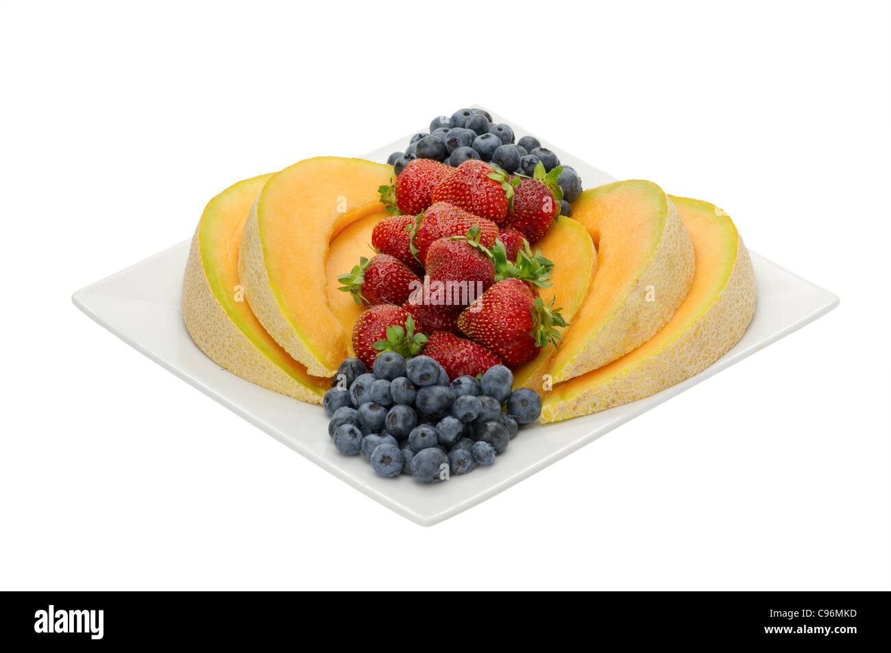 Fruit desert of strawberries and blueberries and cantaloupe on white plate isolated on white Stock Photo
