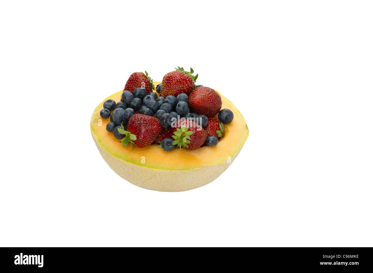 Fresh strawberries and blueberries served in half cantaloupe isolated on white Stock Photo