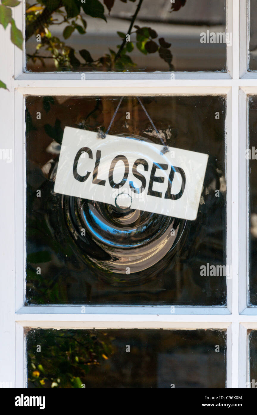 Closed sign behind bullseye glass. Stock Photo