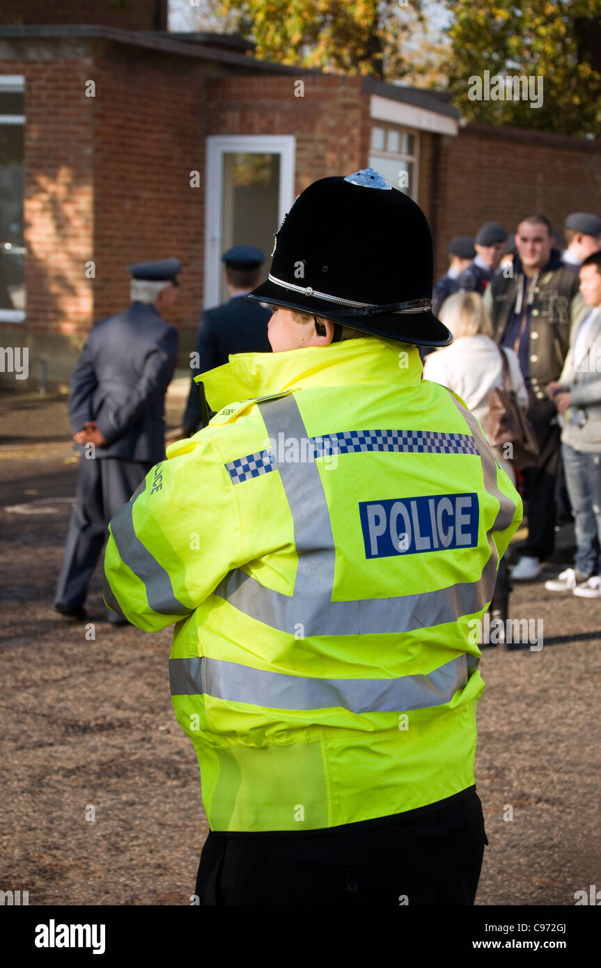 A policeman in a yellow fluorescent jacket watching a crowd of people on Remembrance Day. Stock Photo