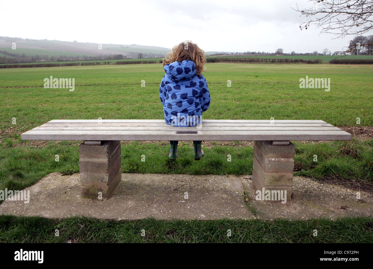 Child alone with thoughts on seat in the Countryside in England. Stock Photo
