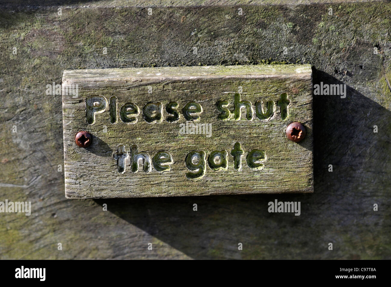 A sign asking people to shut the gate carved in wood UK Stock Photo