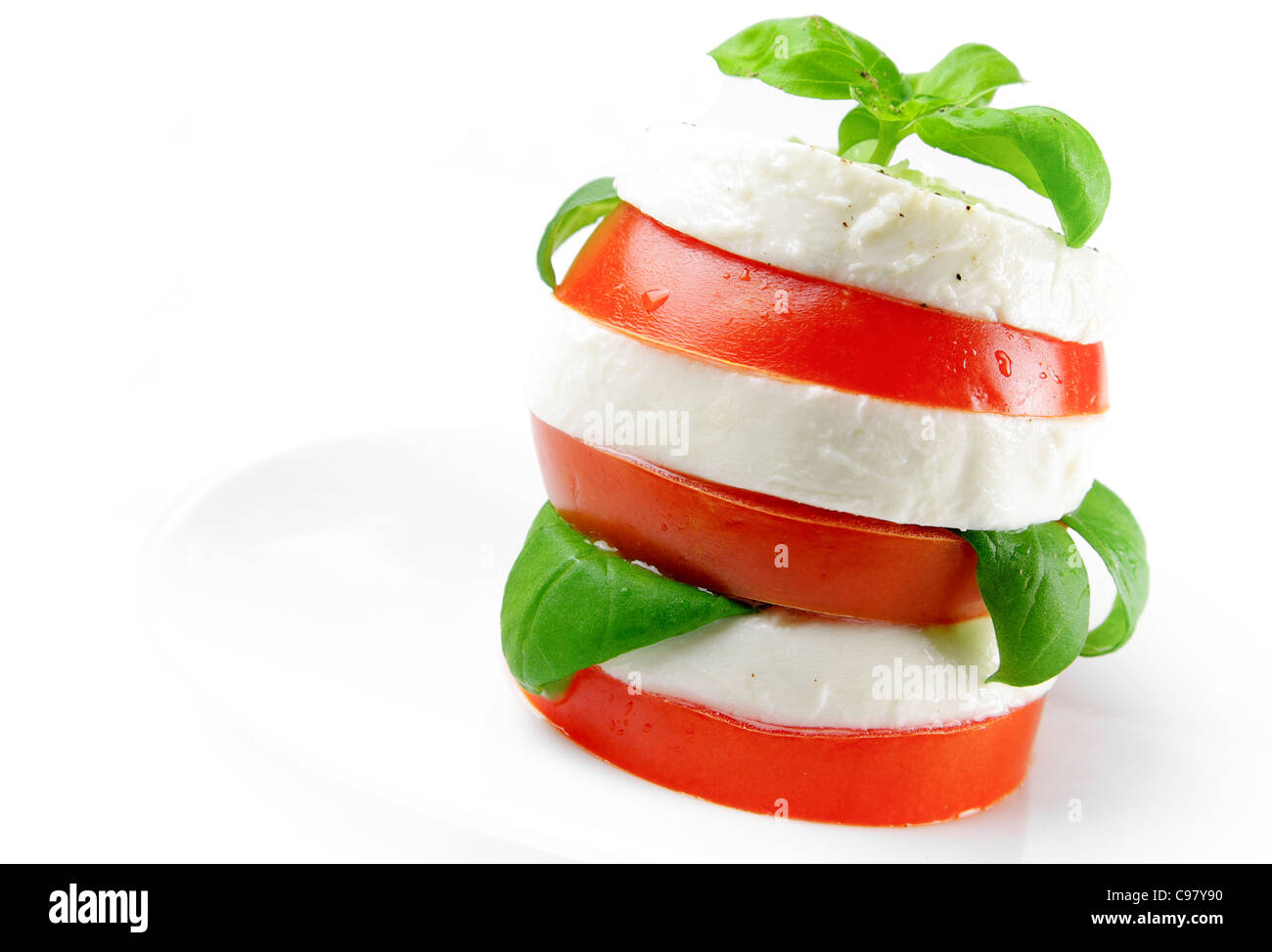 Tomato and mozzarella slices decorated with basil leaves on a plate and ...