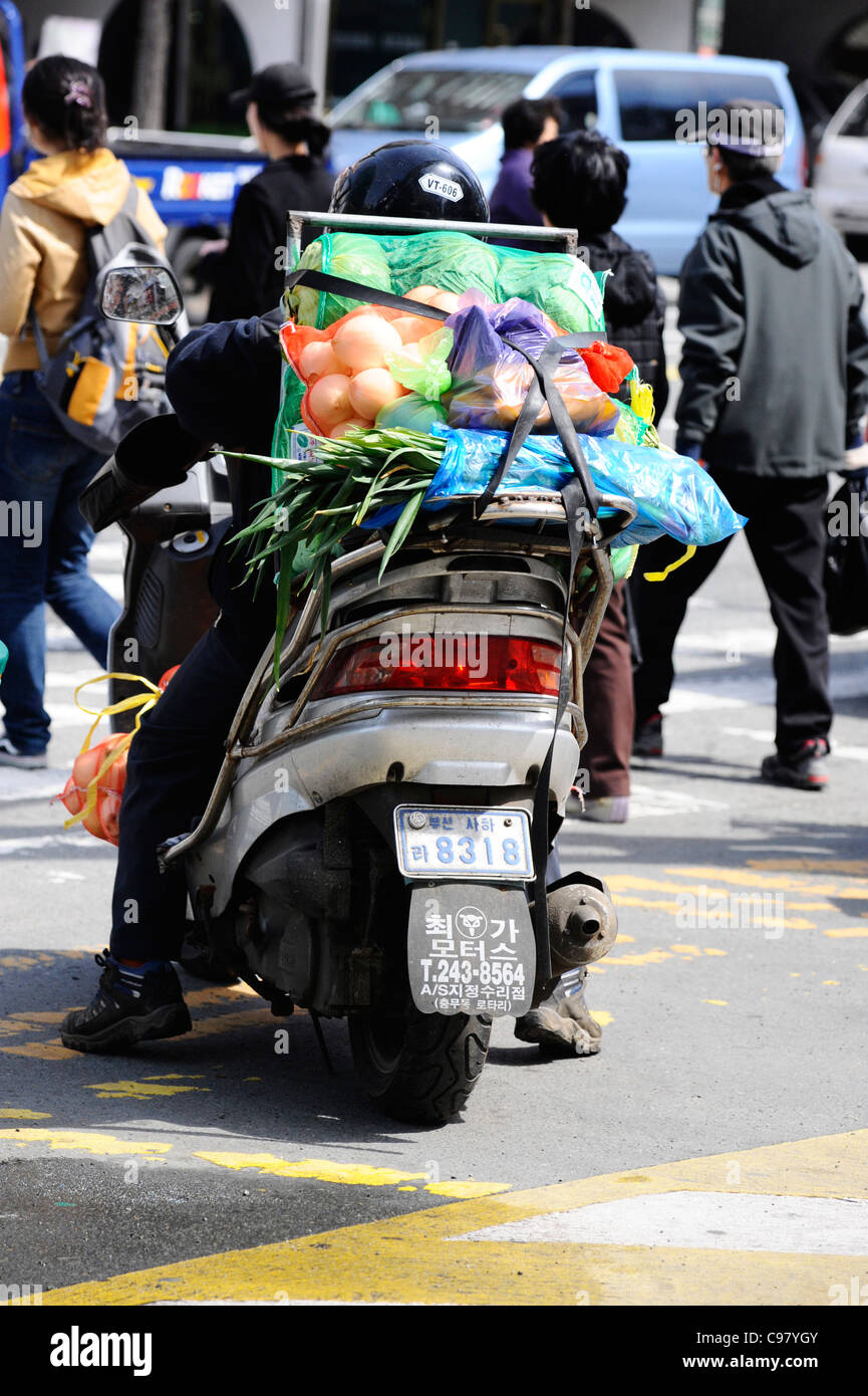 A man on a scooter carrying vegetables in Busan, South Korea. Stock Photo