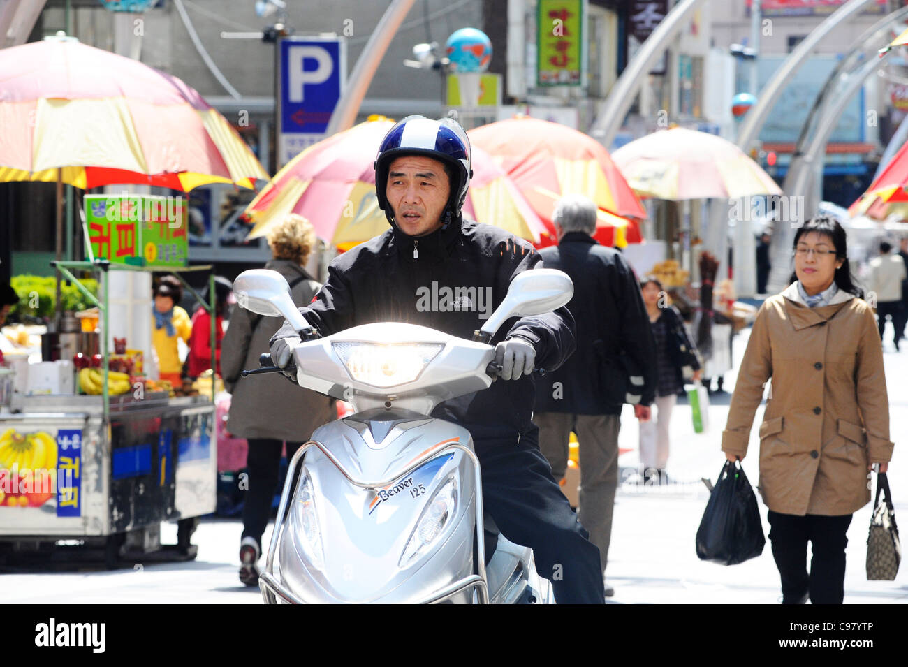 An Asian man riding a Beaver 125 scooter in Busan, South Korea. Stock Photo