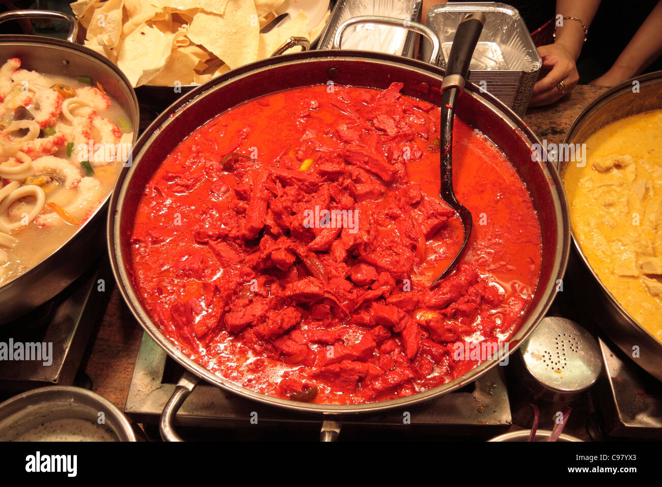 A bright red bowl of Halal Tandorri Chicken on an Indian food stall in Camden Market, in Camden Town, London, UK Stock Photo