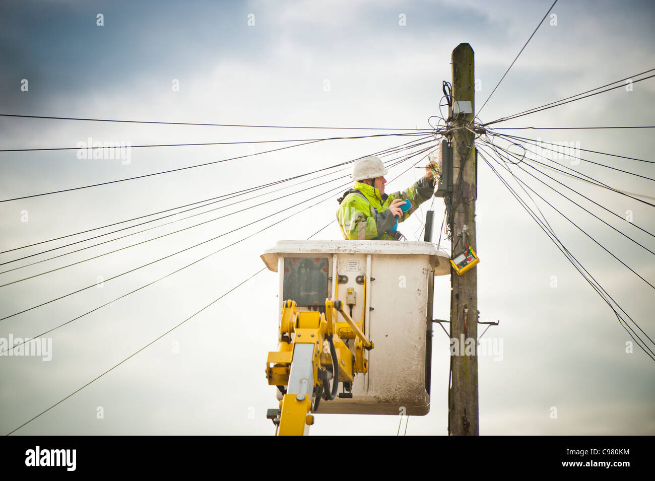 a BT British Telecom engineer repairing a telephone line from an elevated platform, UK Stock Photo
