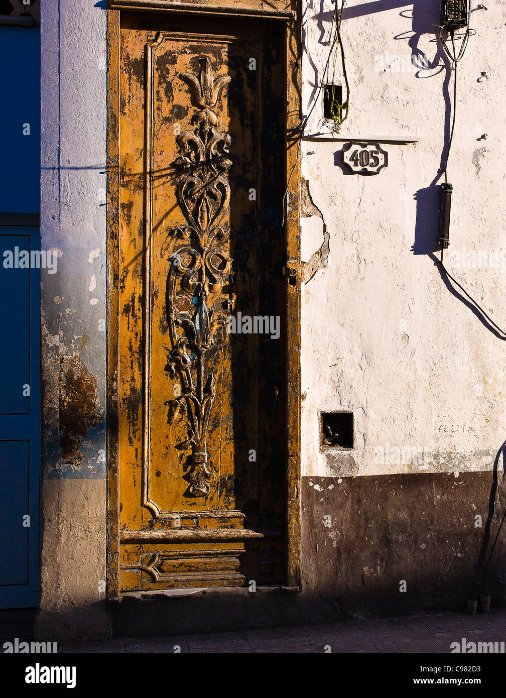 Late afternoon view of ornately carved wooden door on the streets of Havana, Cuba.The door is very weathered with cracks. Stock Photo