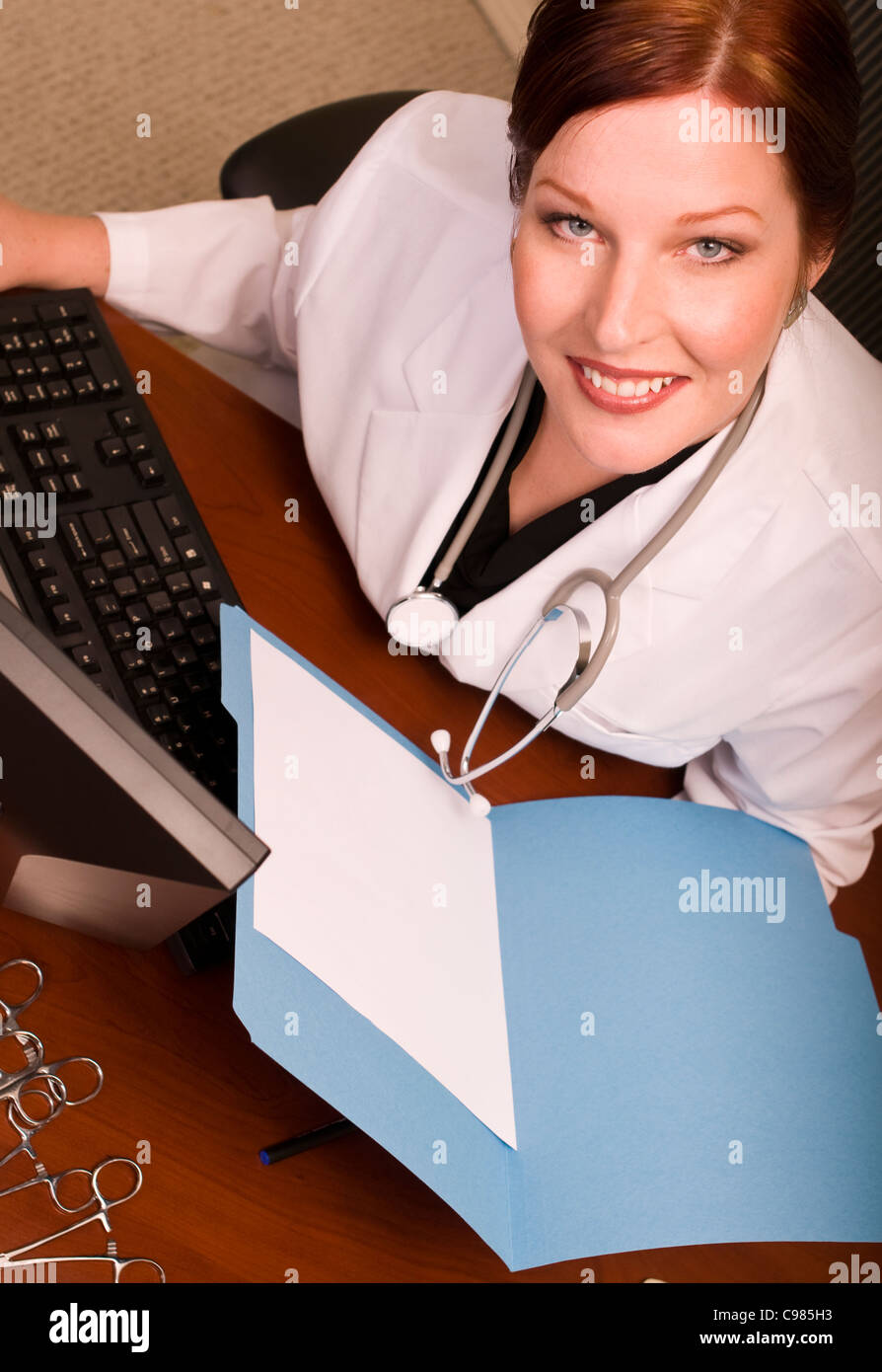 Physician or other medical professional reviewing file at her desk