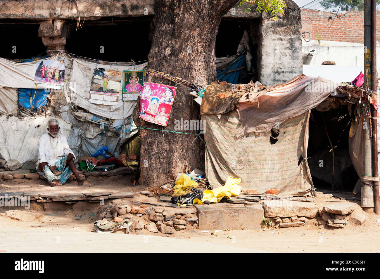 Old indian man on the streets in India next to his makeshift tent home . Andhra Pradesh, India Stock Photo