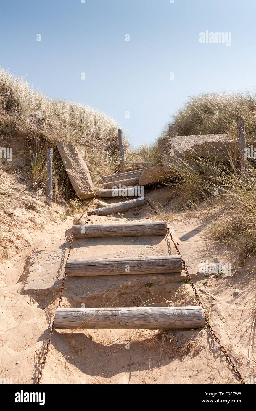 Precarious and wobbly set of wooden steps on chains through steep bank of a tall coastal sand dune Stock Photo