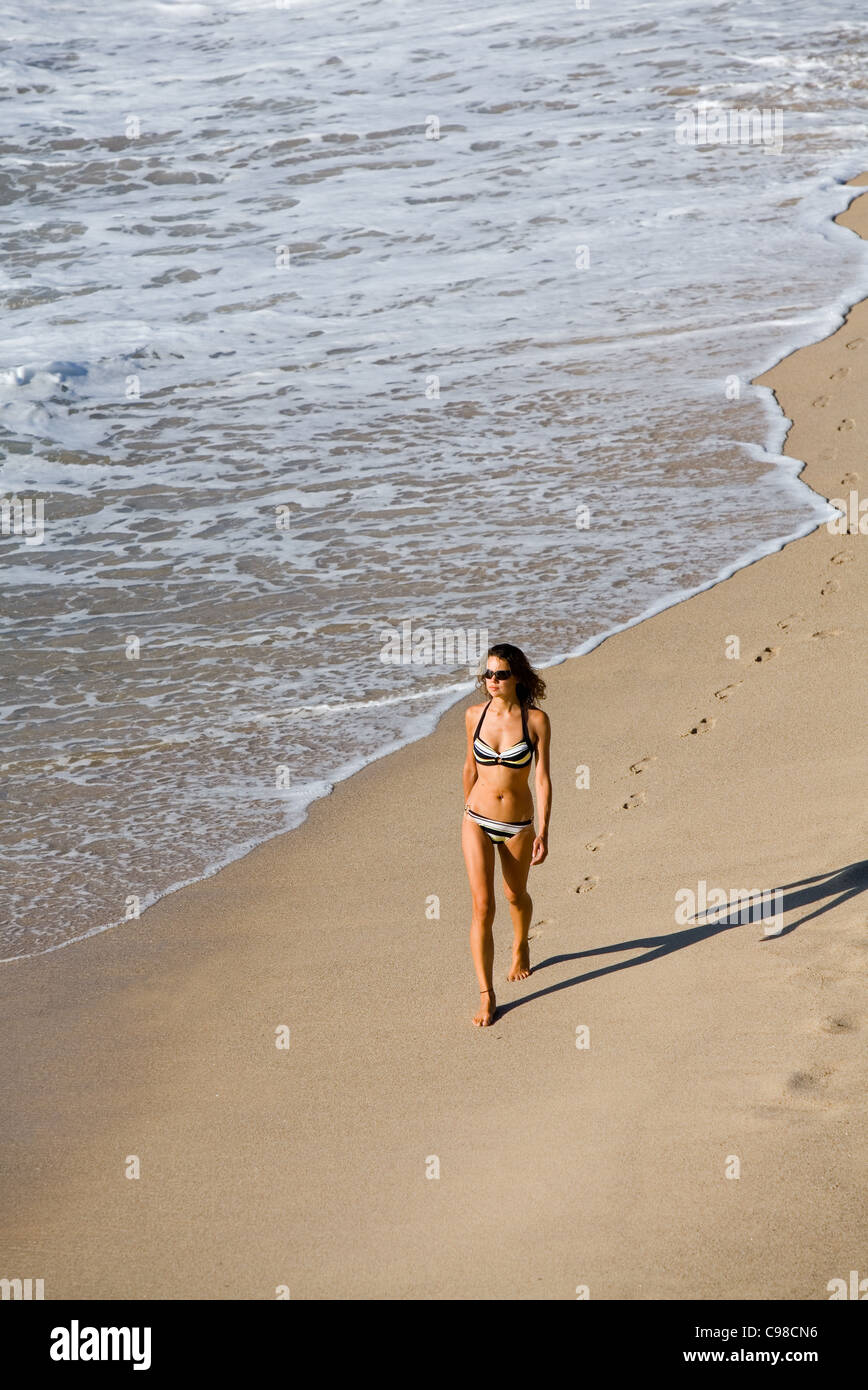Woman in bikini walking along beach.  Bondi Beach, Sydney, New South Wales, Australia Stock Photo