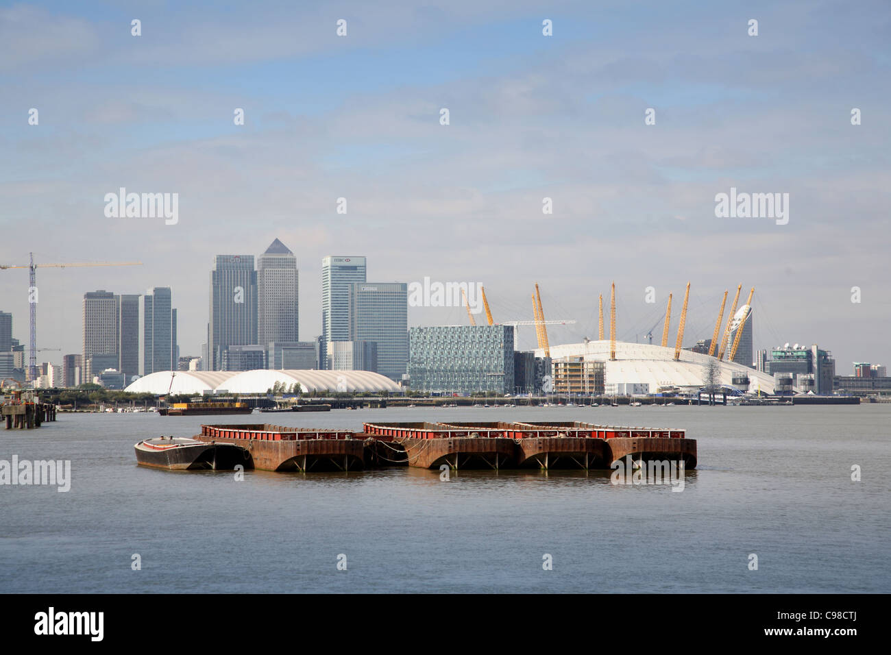 River Thames at Woolwich, London. Shows barges in front of the Canary Wharf development and the Millennium Dome Stock Photo