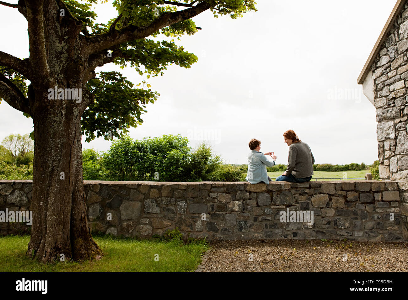 Father and son sitting on stone wall Stock Photo