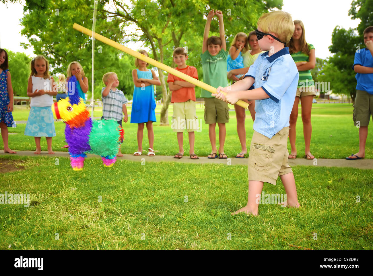 Young boy at an outdoor party hitting a pinata Stock Photo - Alamy