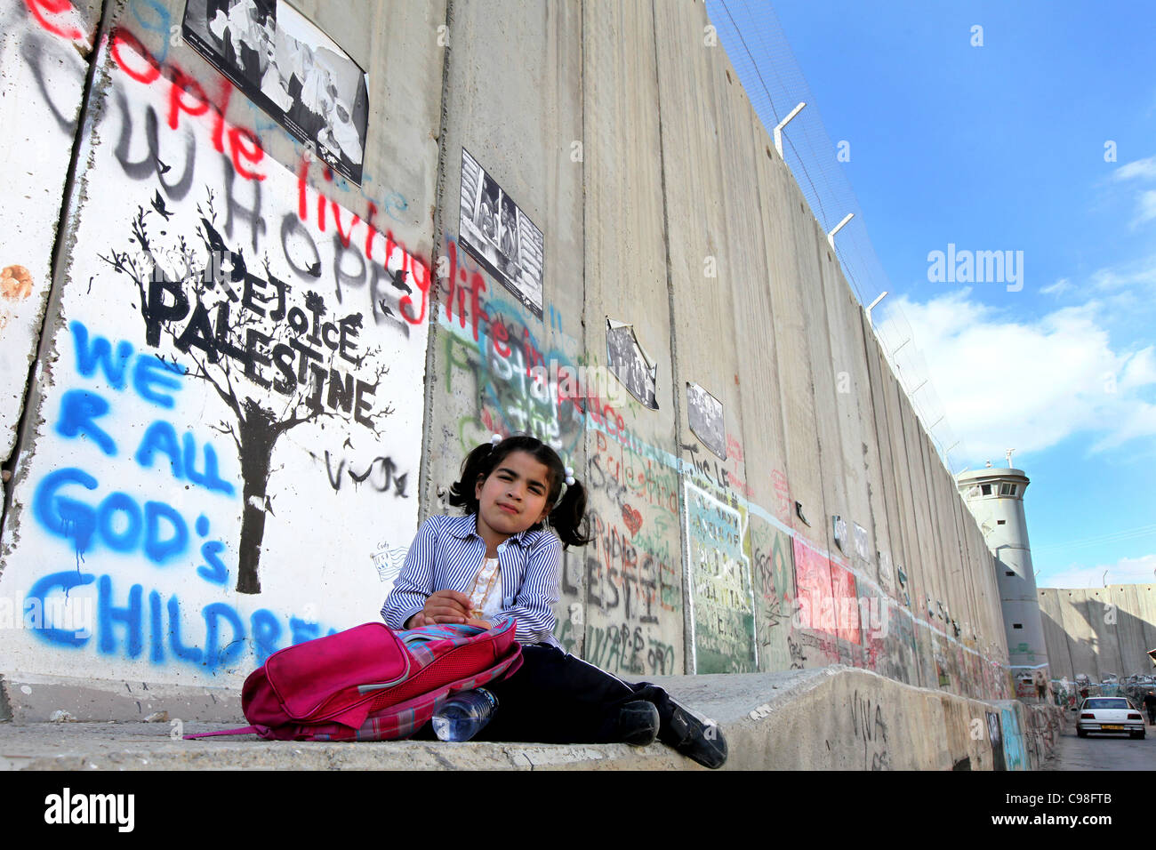 Girl sitting at the Israeli separation wall. This wall divides Palestinian lands in the West Bank near the Bethlehem checkpoint Stock Photo