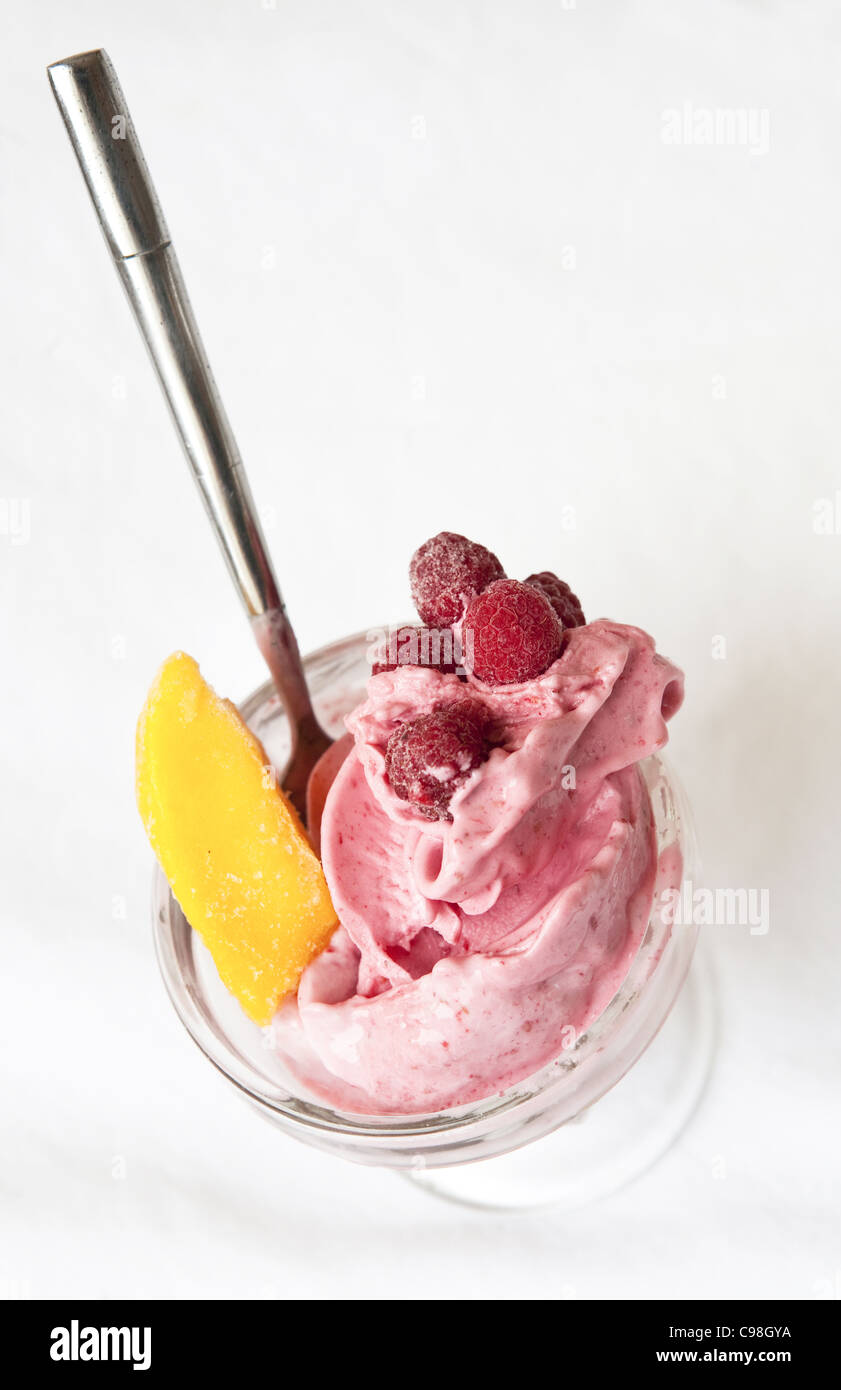 Crisp photo of a Raspberry peach frozen yogurt in a glass dish with a spoon. Stock Photo