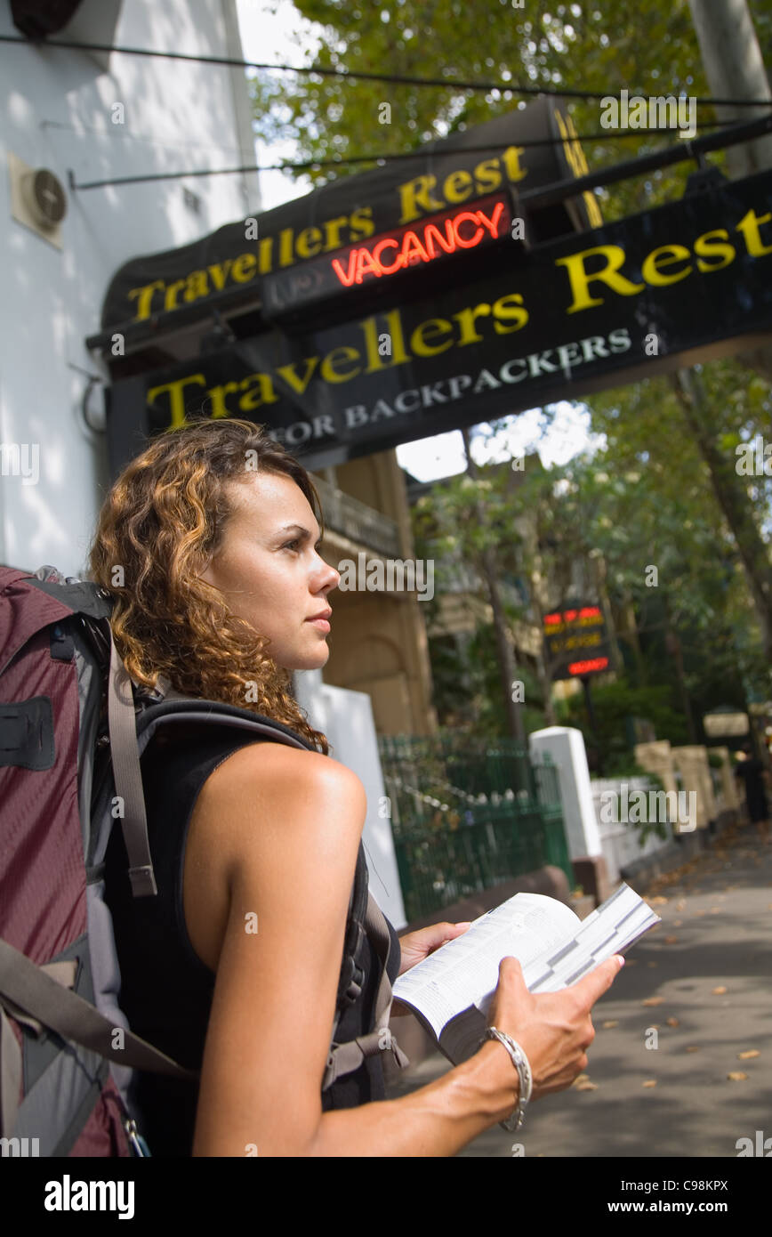 Backpacker with guidebook standing outside a hostel. Kings Cross, Sydney, New South Wales