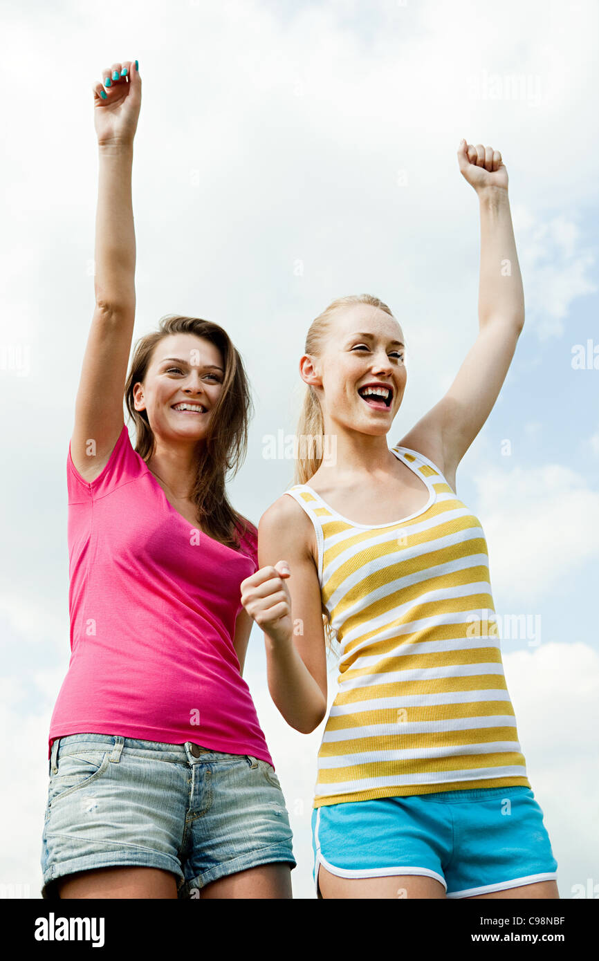 Young women cheering with arms raised Stock Photo - Alamy