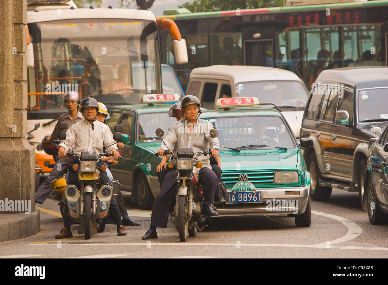 GUANGZHOU, GUANGDONG PROVINCE, CHINA - Scooters, taxis and buses wait at traffic light, in city of Guangzhou. Stock Photo