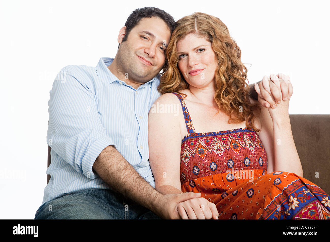 Couple relaxing on sofa against white background Stock Photo - Alamy