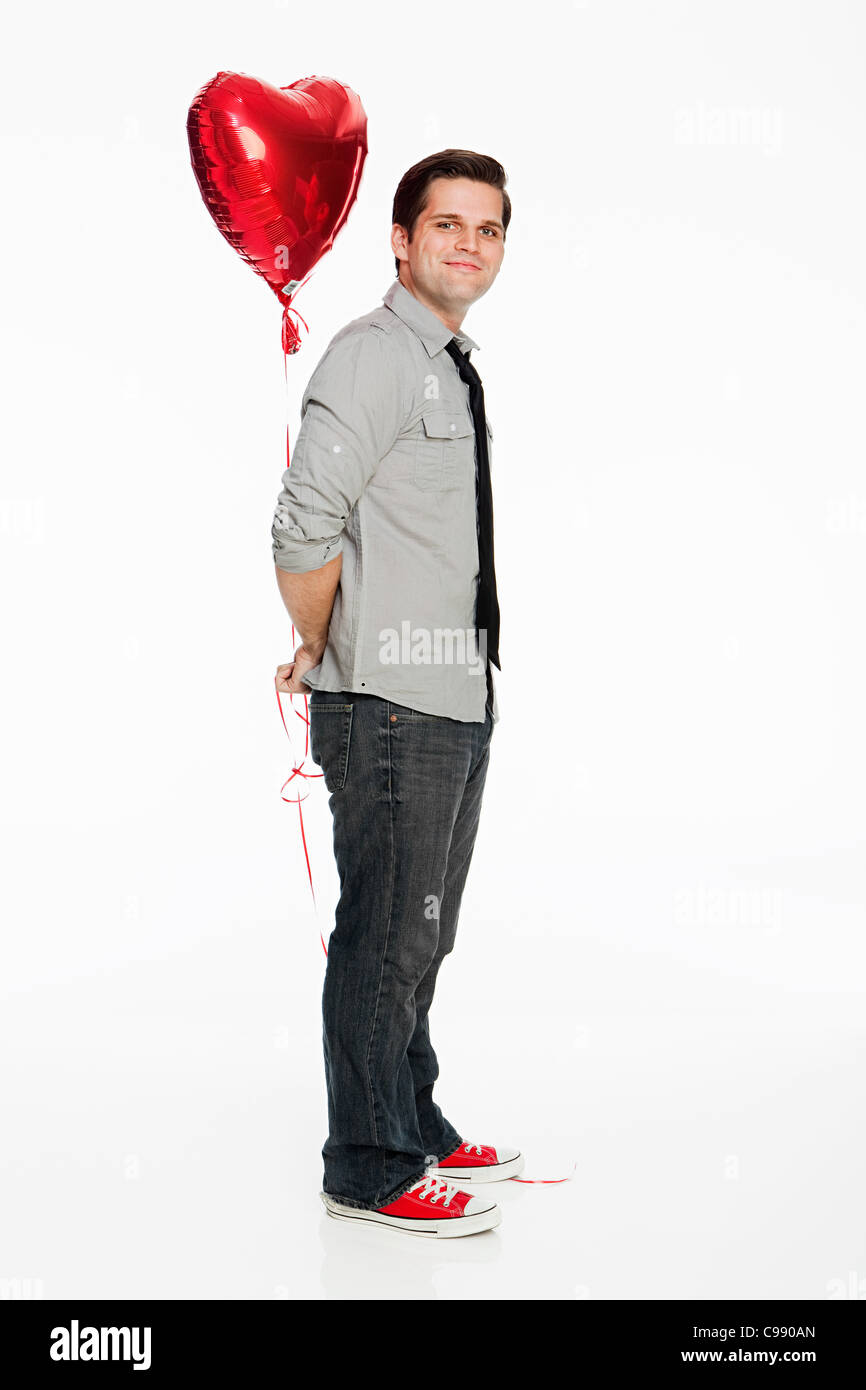 Young man holding balloon against white background Stock Photo