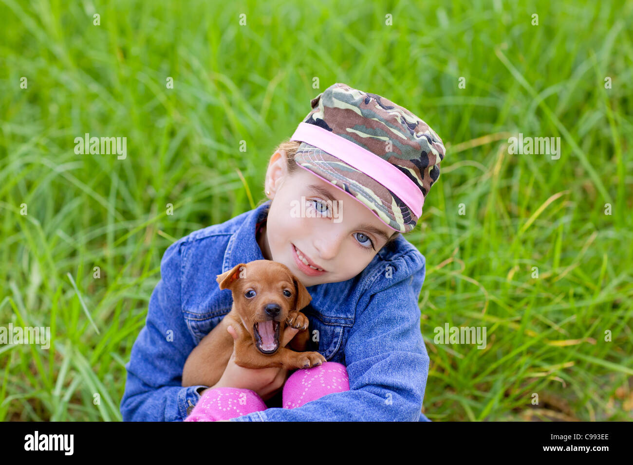 little girl with pet puppy mascot mini pinscher in outdoor green grass ...