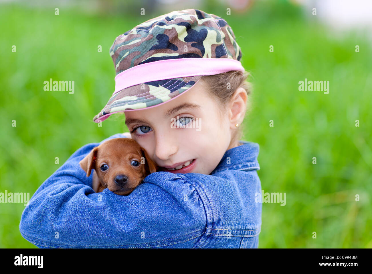 little girl with pet puppy mascot mini pinscher in outdoor green grass ...