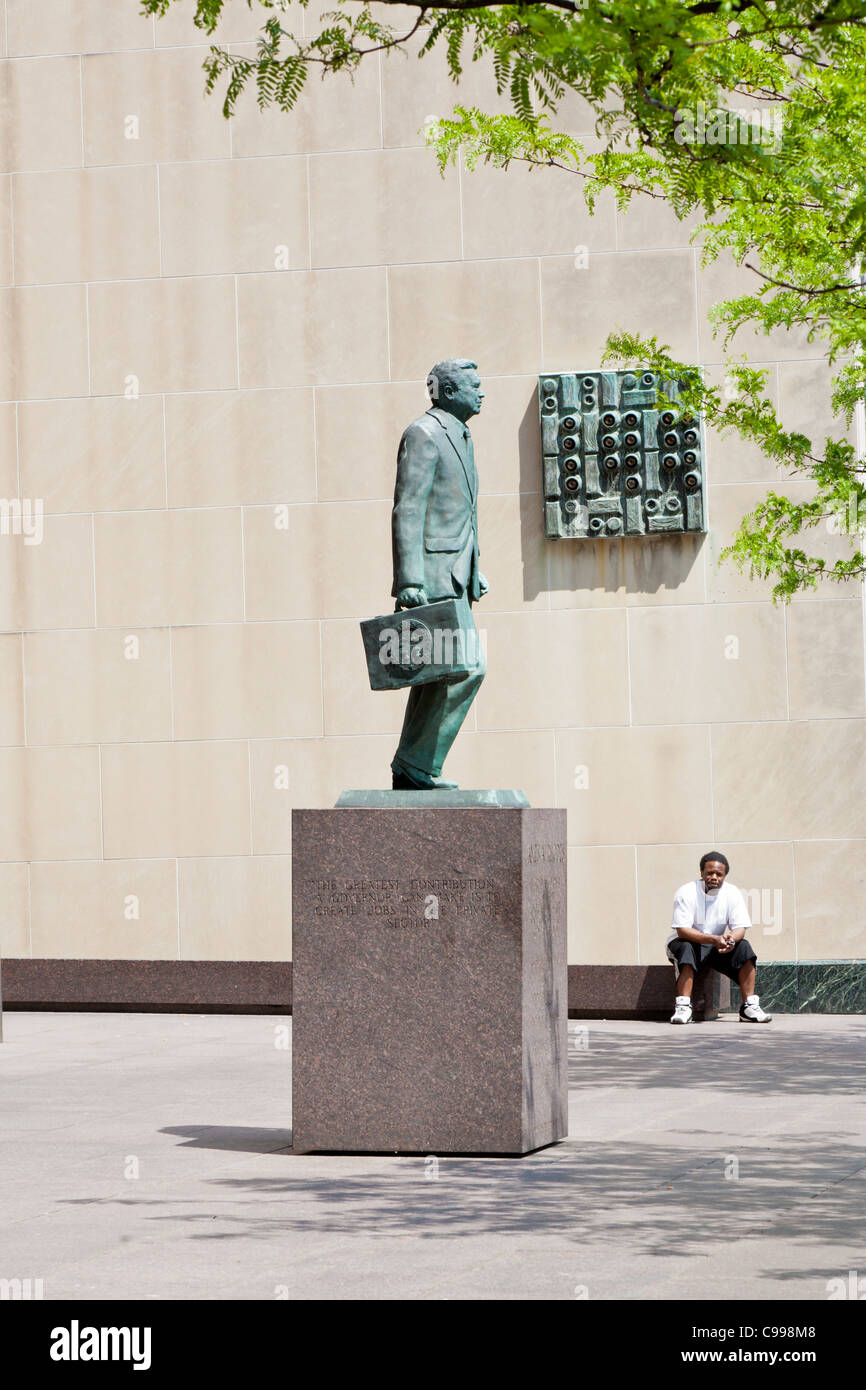 Black man sits looking at statue of James A. Rhodes in front of the State Office Tower in downtown Columbus, Ohio. Stock Photo