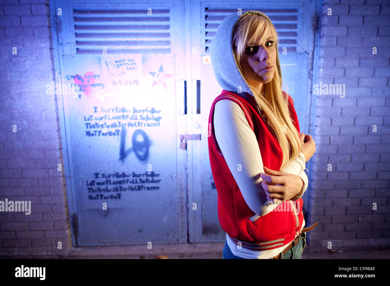 A 16 year old blonde haired slim teenage girl, alone in a dingy urban location, UK Stock Photo