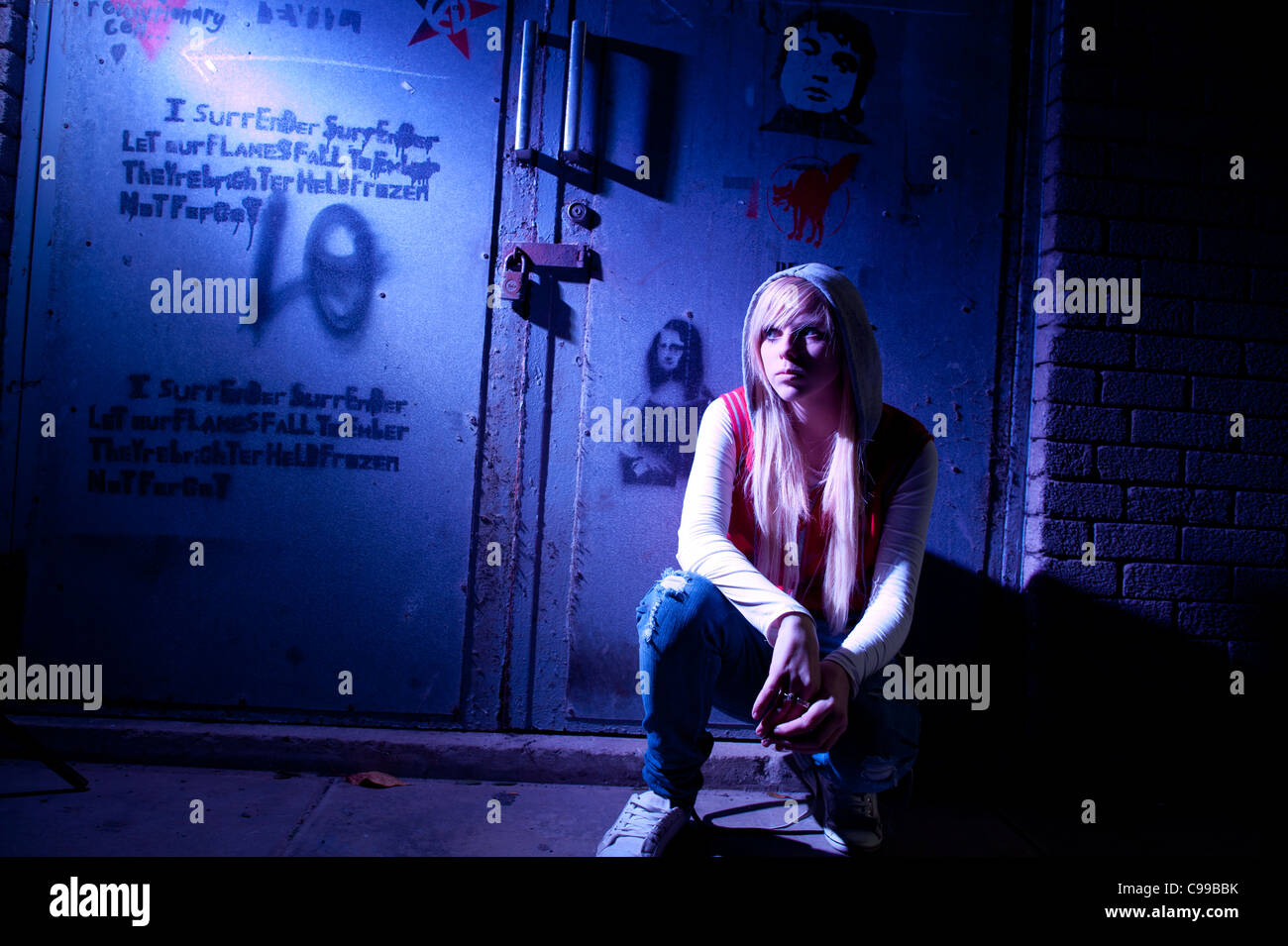 A 16 year old blonde haired slim teenage girl, alone in a dingy urban location, UK Stock Photo