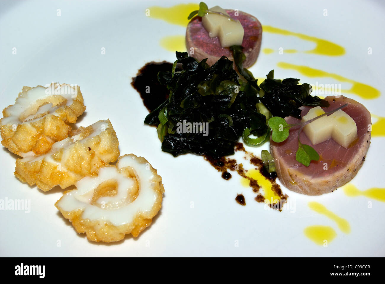 Seared rare cooked yellowfin tuna crispy squid slices wakame seaweed salad wasabi jelly cubes seafood appetizer Stock Photo