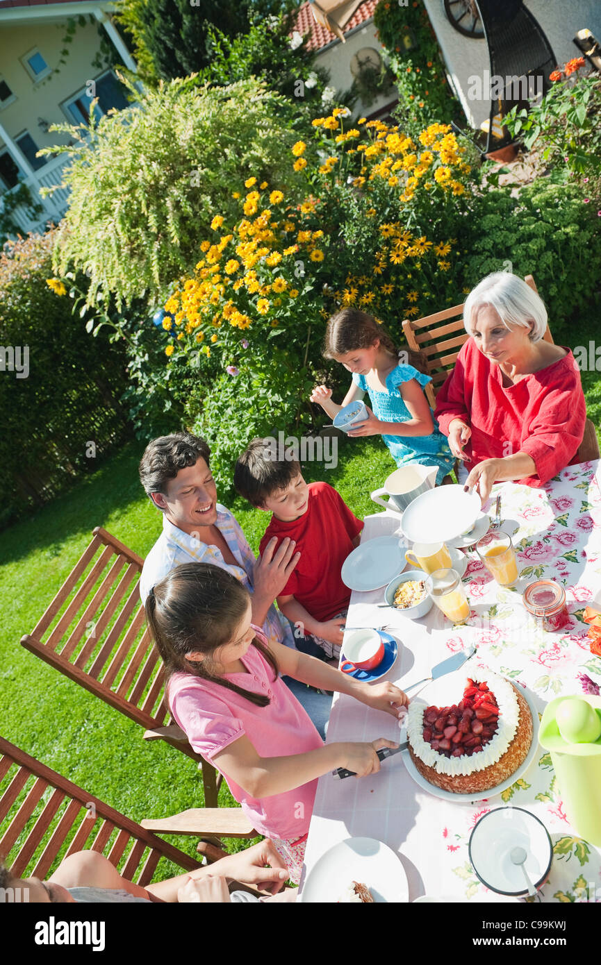 Germany, Bavaria, Family having coffee and cake in garden, smiling Stock Photo