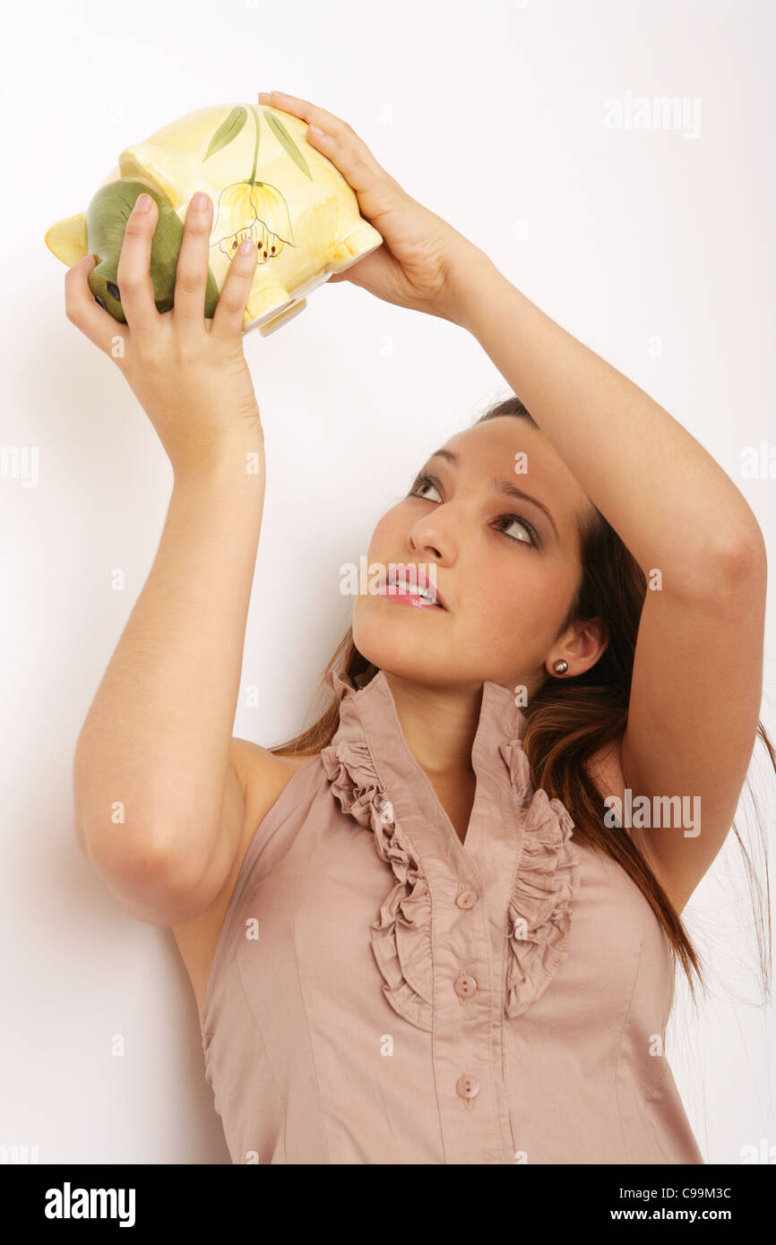 Pretty teenage girl holding a piggy bank above her head Stock Photo - Alamy