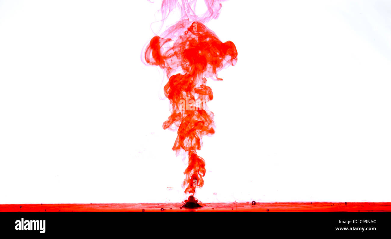 Side view of red coloured ink squirted into a clear tank of water. Stock Photo