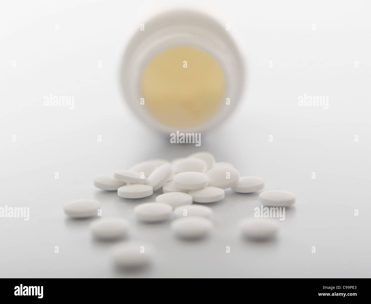 White pills spilling out of bottle, close-up Stock Photo