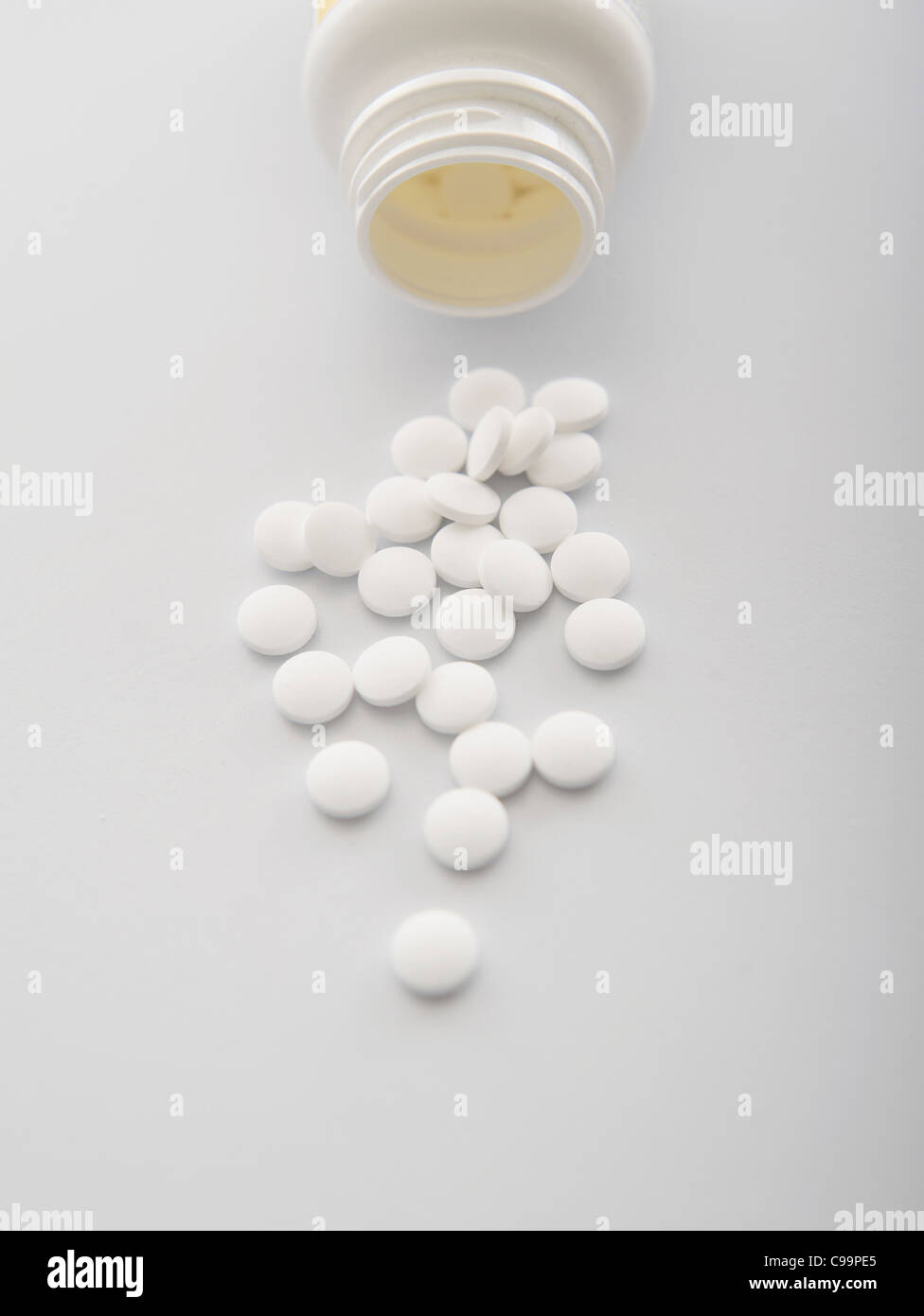 White pills spilling out of bottle, close-up Stock Photo