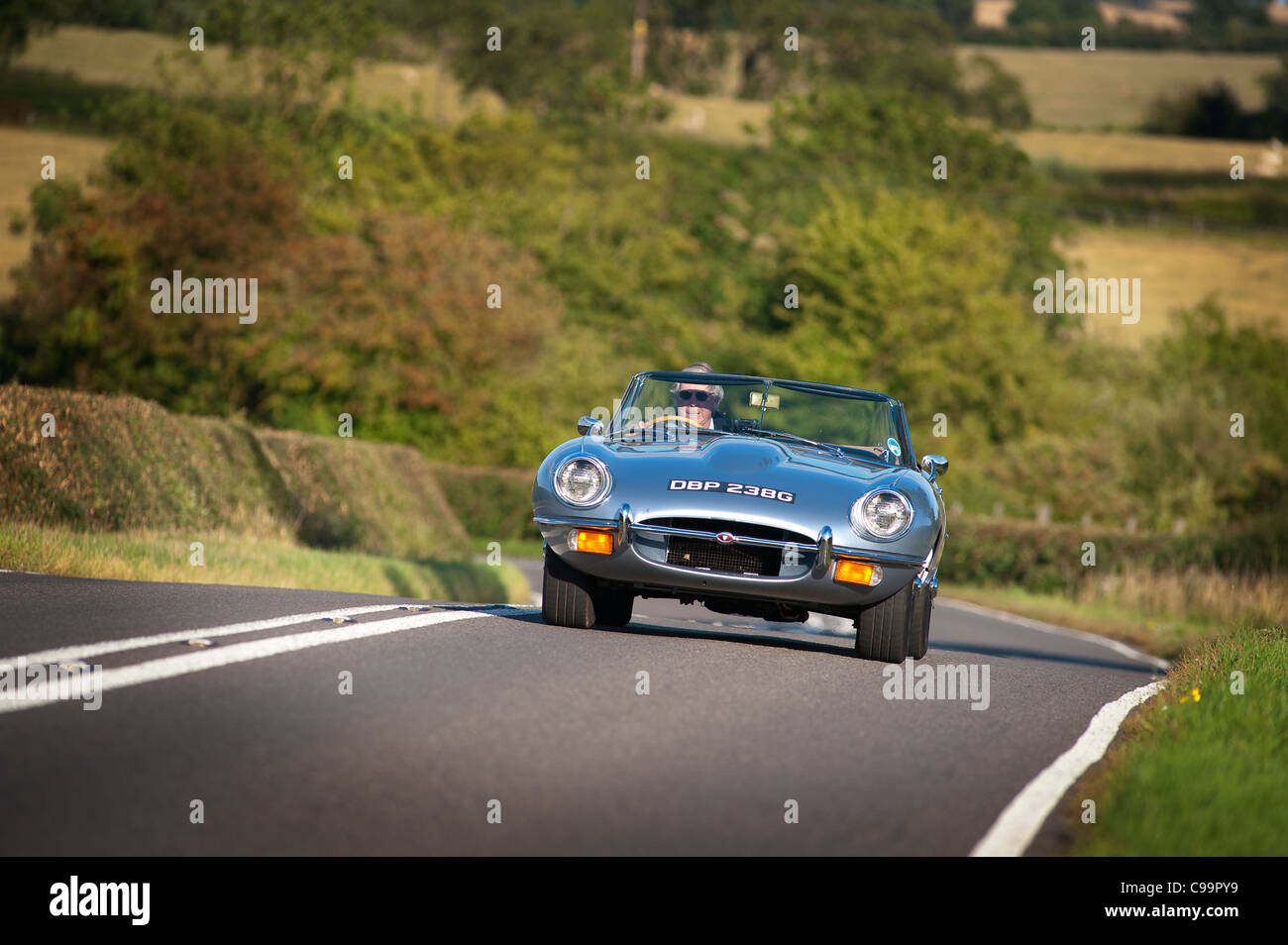 Jaguar E-Type sports car being driven through rural England in the summertime. Stock Photo