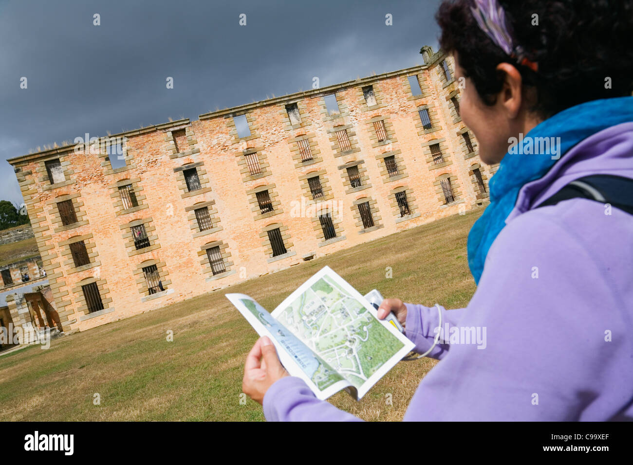 A woman looks toward the ruins of the Penitentiary at the Port Arthur Historic Site. Port Arthur, Tasmania, Australia Stock Photo