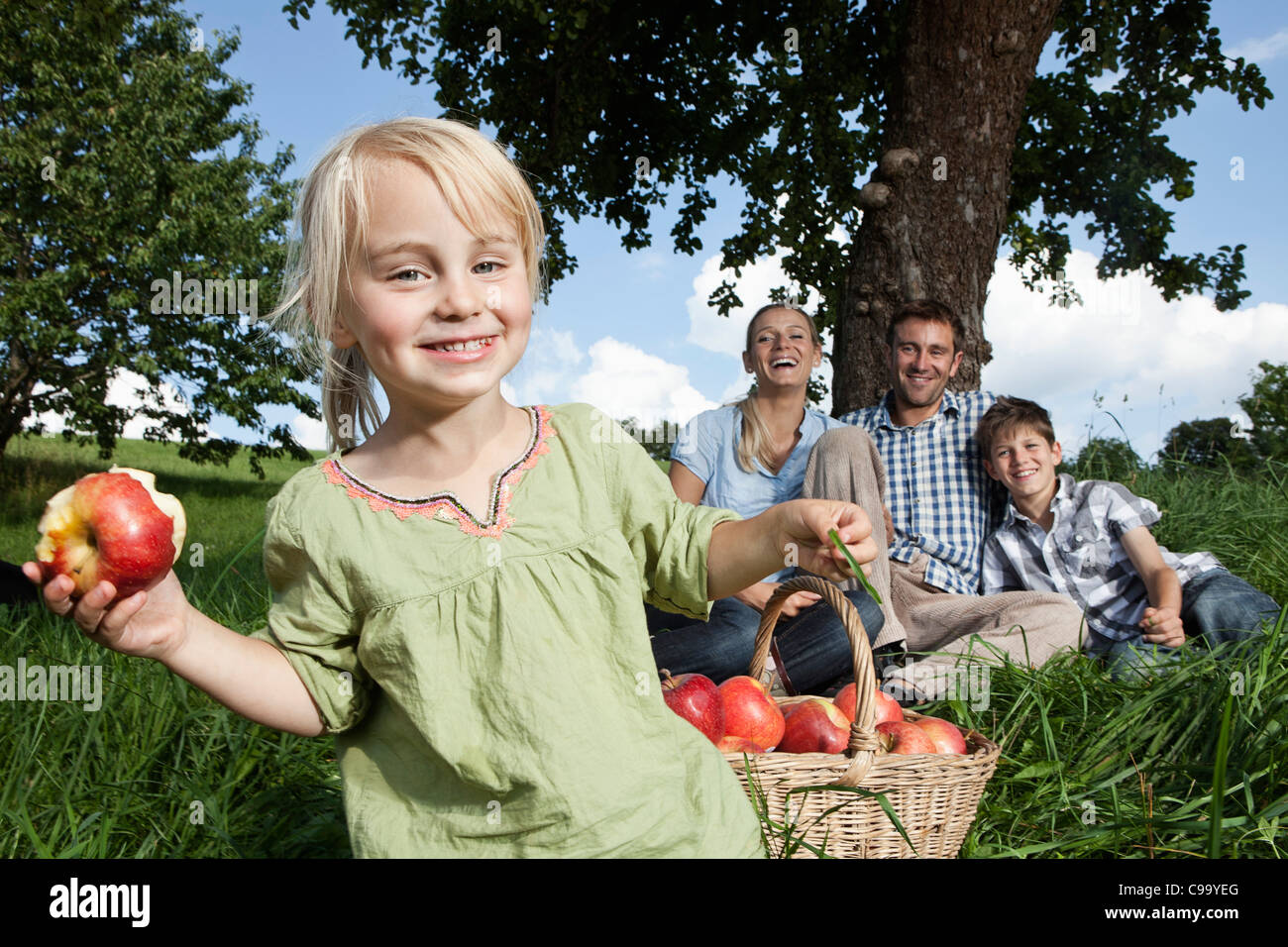 Germany, Bavaria, Altenthann,Girl with basket of apples, family with dog in background Stock Photo