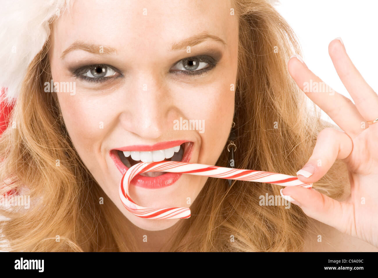 Blond excited pinup woman in Christmas outfit holding candy cane stick Stock Photo