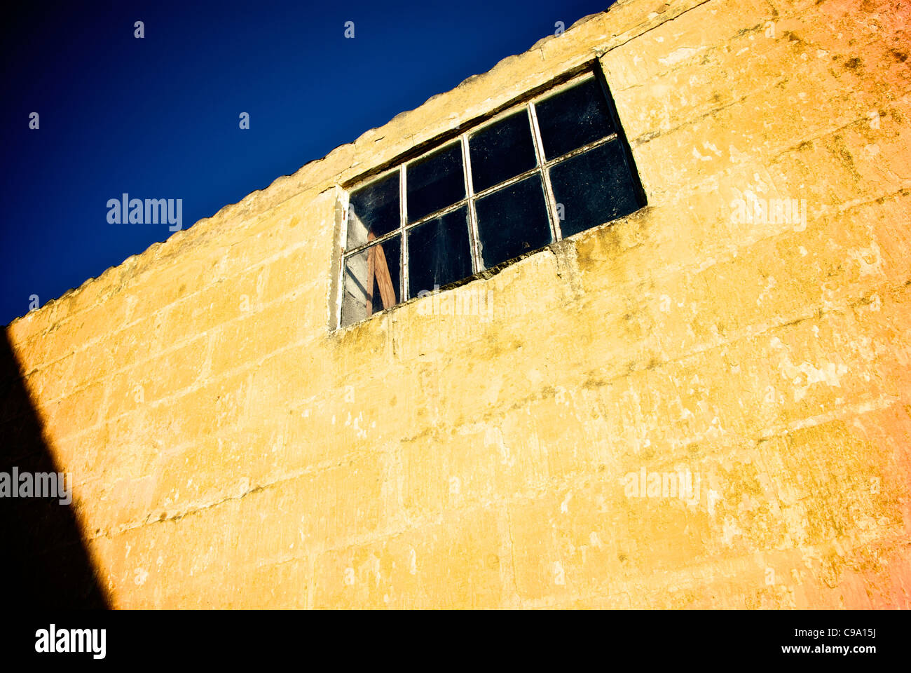 OLD YELLOW WALL WITH WINDOW Stock Photo